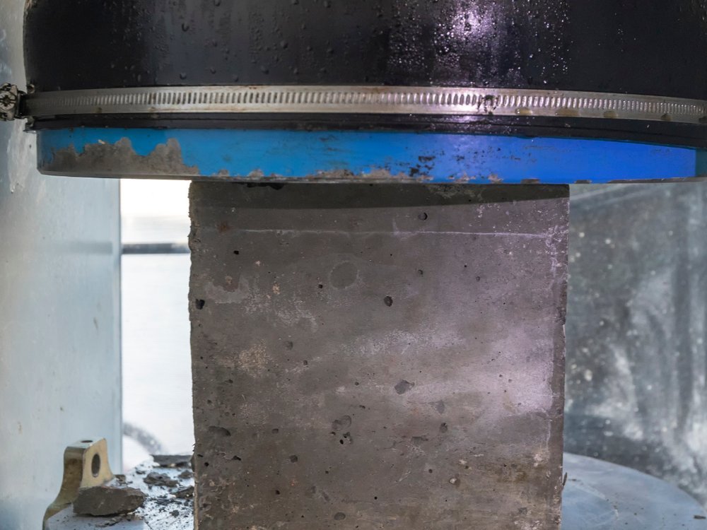 Corpo de prova de concreto posicionado na prensa para ensaio de compressão